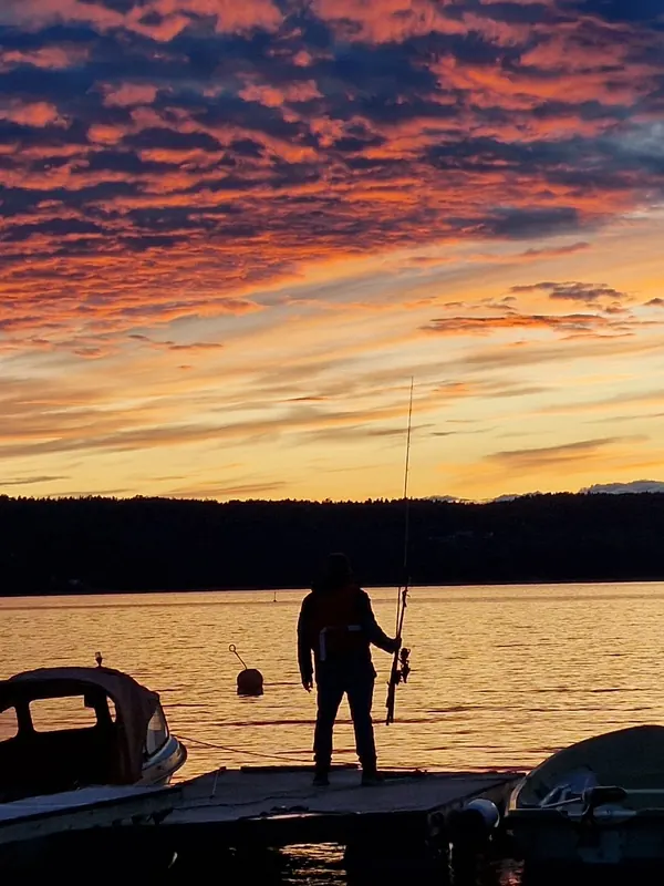 Fischer im Sonnenuntergang auf dem Steg am Bergsee