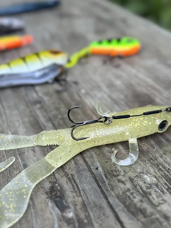 Gummiköder mit Jighaken und bunte Wobbler auf dem Holztisch