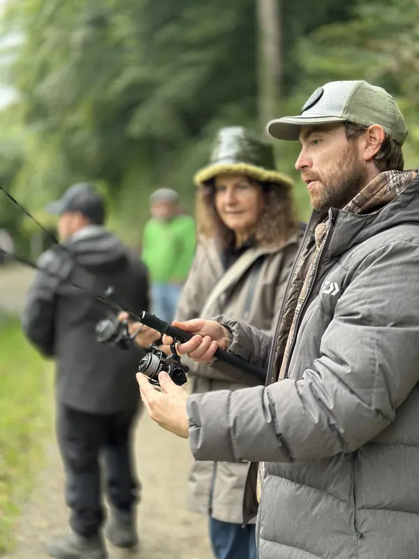 Instruktor begleitet die Teilnehmenden beim Fischen am Teich