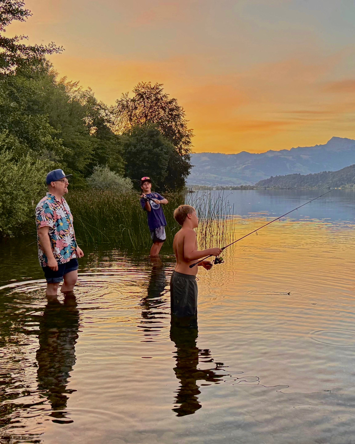 Familie beim Angeln am See in der Abendsonne
