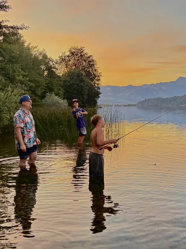 Vater und Söhne fischen im Abendrot knietief im Zürichsee